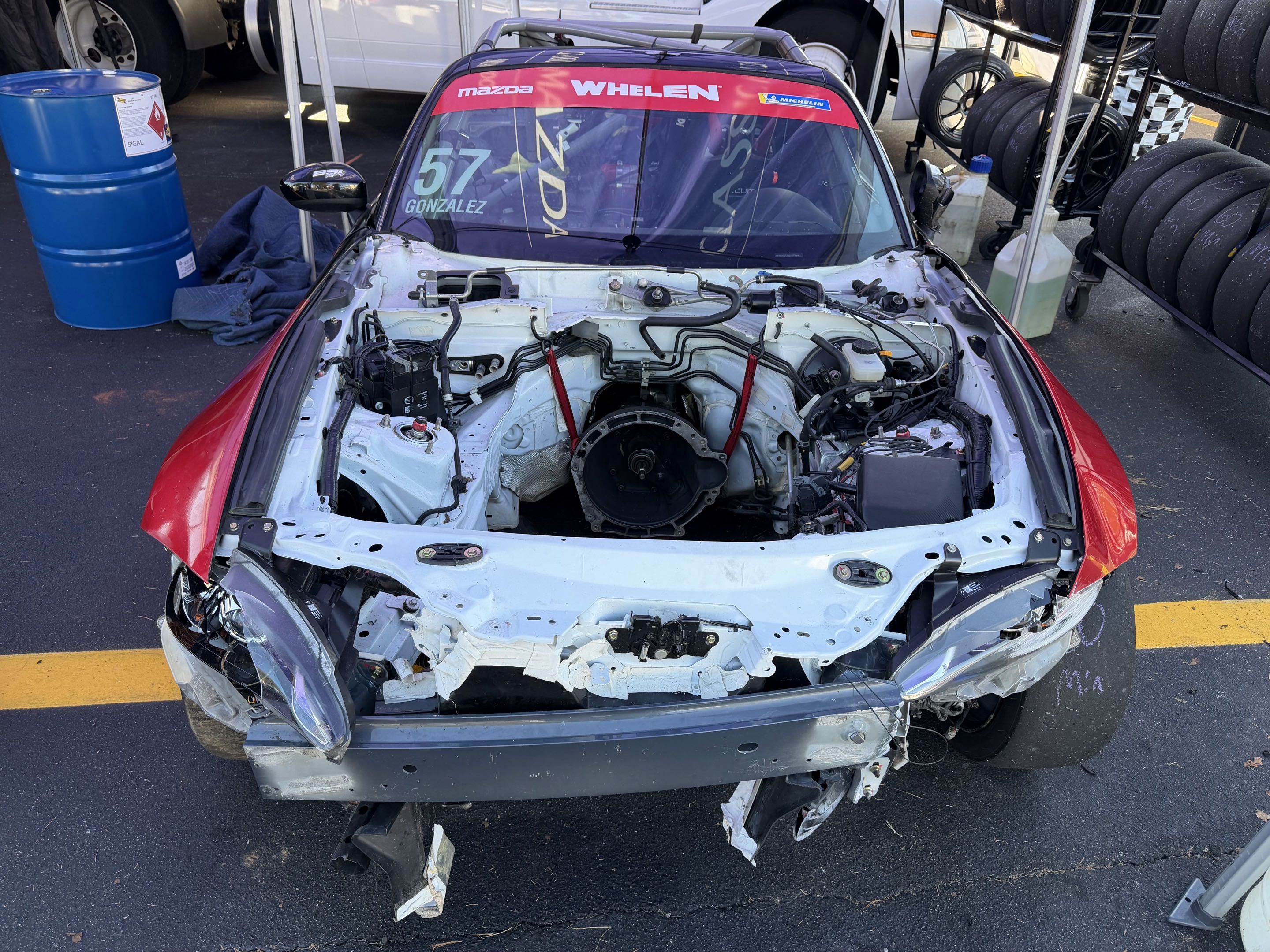 A fairly destroyed Mazda MX-5 race car with the engine removed